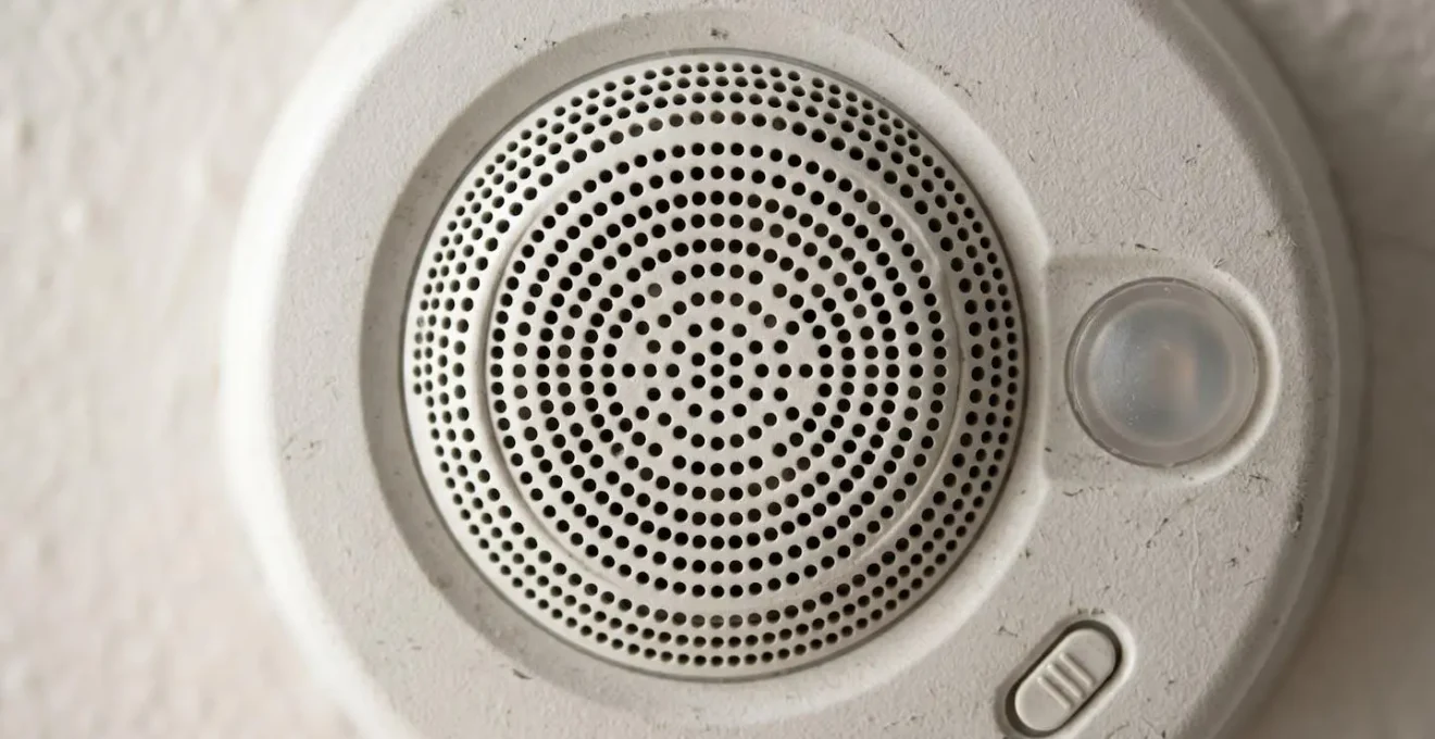 Détail macro d'un détecteur de fumée moderne avec indicateur LED et grille de ventilation